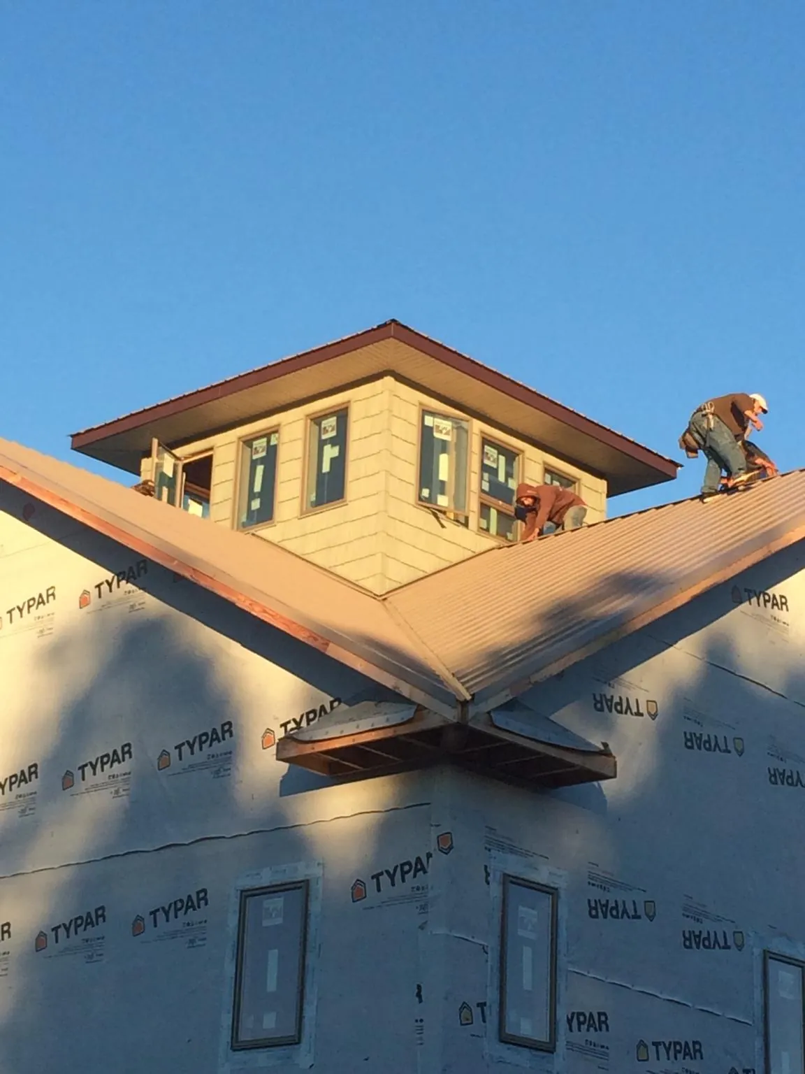 Roofers working around a rooftop cupola on a new metal roof at sunset — Roof Waterproofing in Colton by Roofing Brothers